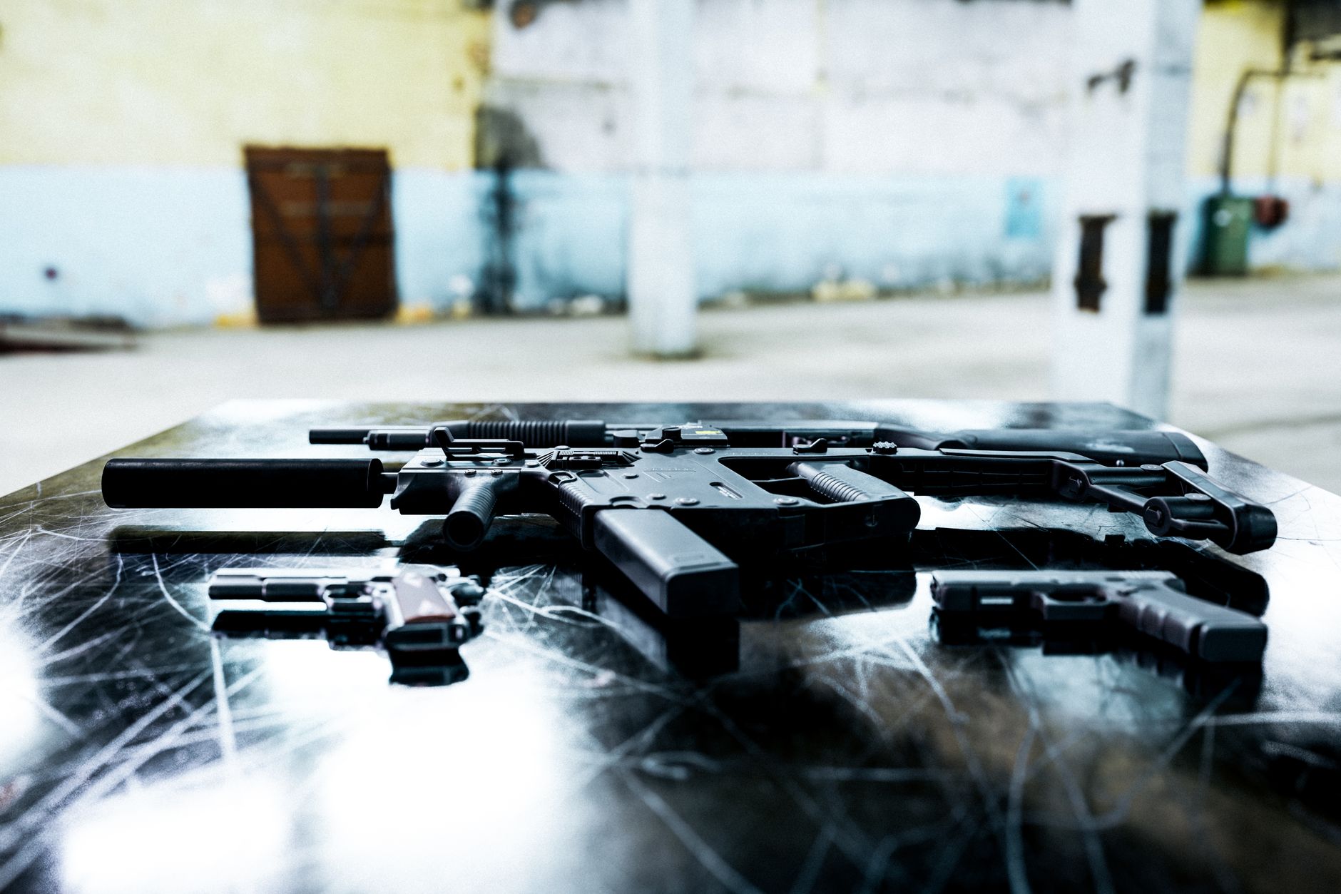 Diversas armas de fogo expostas sobre uma mesa metálica em ambiente industrial