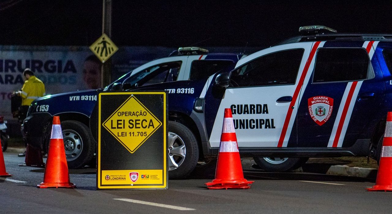 Viaturas da Guarda Municipal e cones sinalizam um ponto de fiscalização policial durante a noite.