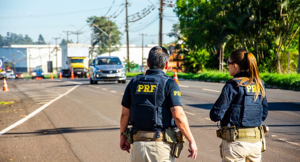 Agentes da Polícia Rodoviária Federal monitoram o tráfego em uma rodovia durante o dia.