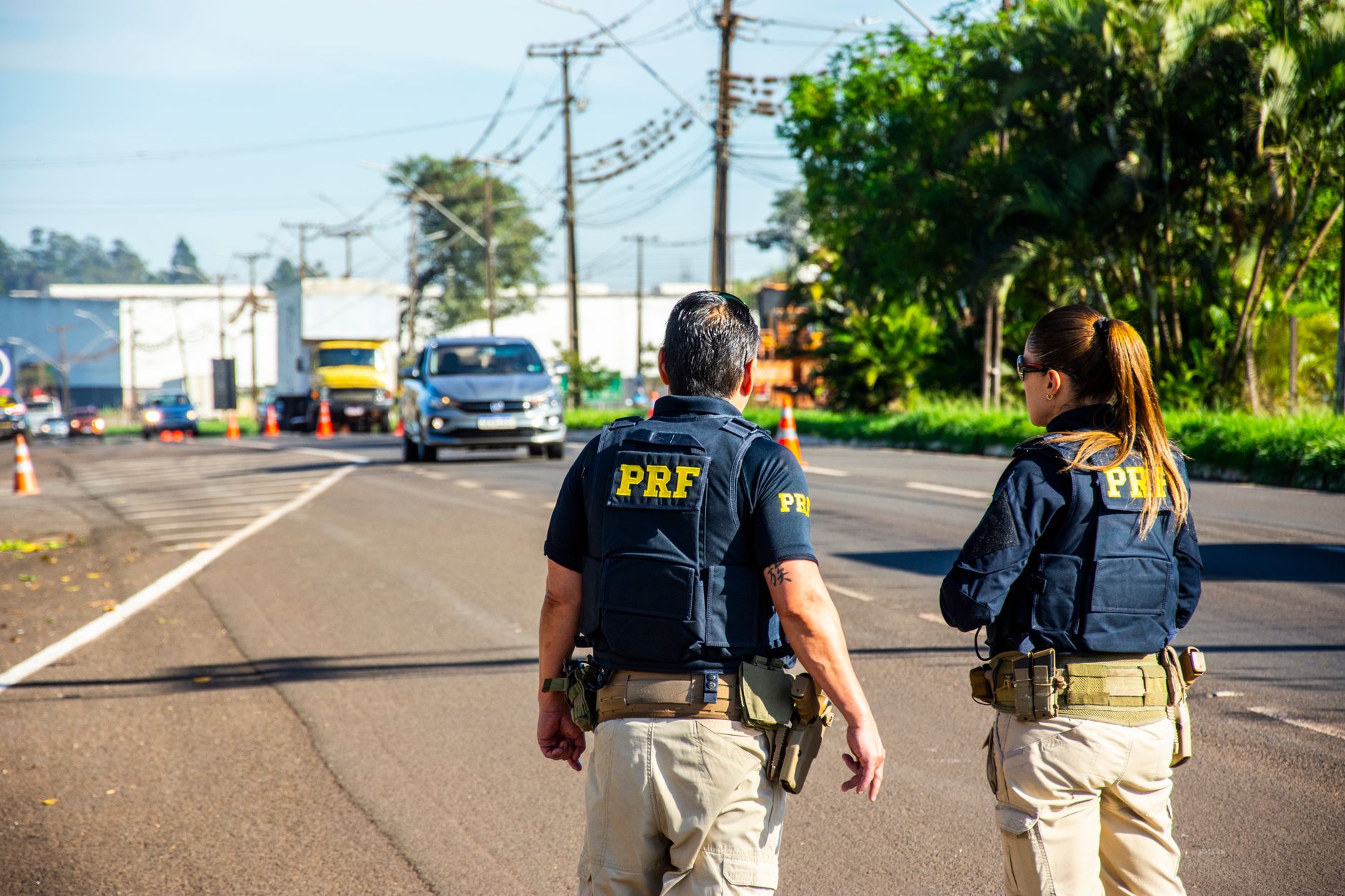 Agentes da Polícia Rodoviária Federal monitoram o tráfego em uma rodovia durante o dia.